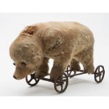 A late 19th/early 20th century blonde plush bear on wheels:, possibly Steiff,