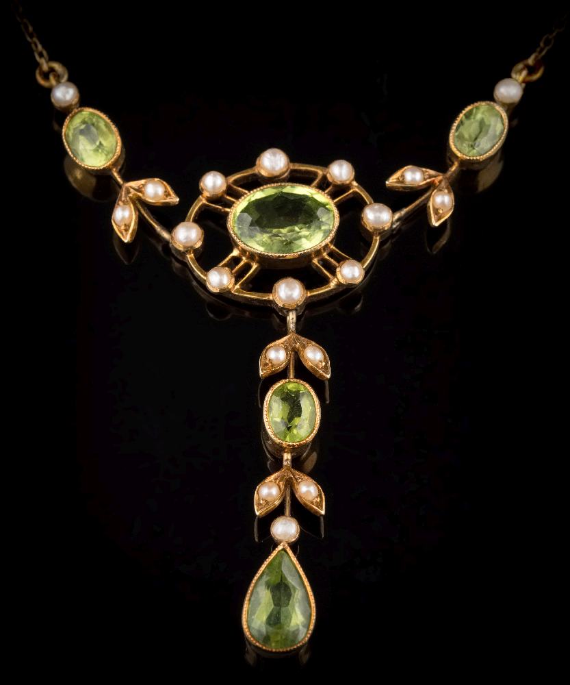 An Edwardian peridot and seed pearl lavalier: the central, oval peridot approximately 9mm long x 6.
