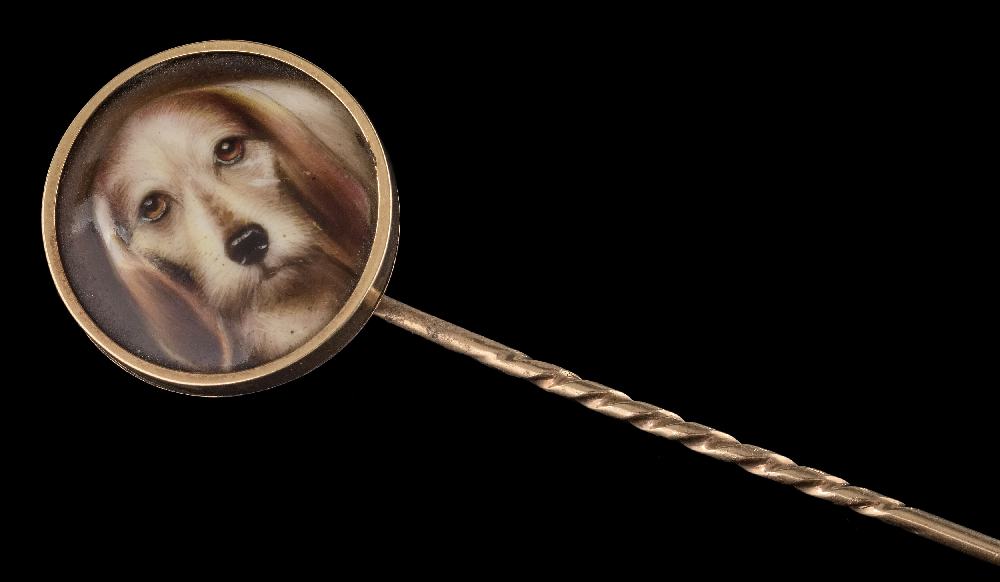 A stick pin with circular enamelled plaque depicting head of hound: in closed back setting,