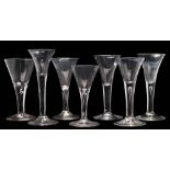 Seven wine glasses: each trumpet shaped bowl tapering into a straight stem,