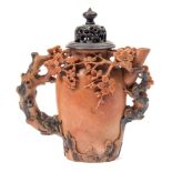 A Chinese soapstone wine pot: carved with flowering prunus and rockwork,15 cm and wood cover.