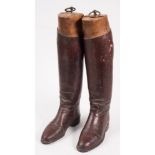 A pair of brown leather riding boots and wooden boot trees:..