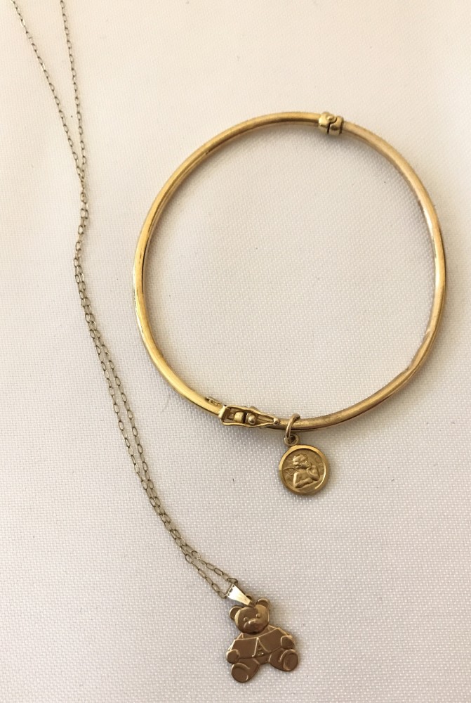 A 9ct gold thin bangle with small circular cherub charm.