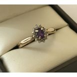 A 9ct gold dress ring set with central amethyst surrounded by 11 small diamonds.