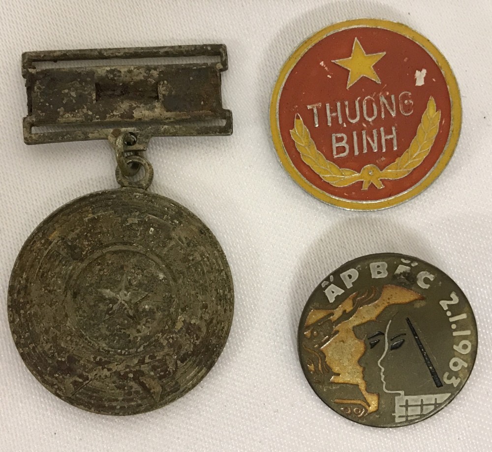 2 Vietnam War Era N.V.A/Vietcong badges and a medal found in a street market in Saigon.