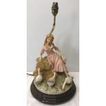 A heavy modern resin figurine lamp base of a girl with geese, mounted on wooden plinth.