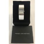 A ladies boxed French Connection wristwatch with white leather strap.