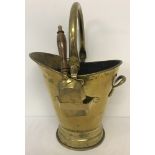 A large brass coal scuttle and integral shovel with wooden handle, hammered finish.