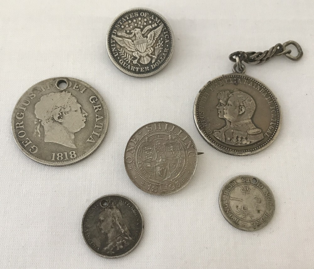 A small collection of silver and white metal coins some made into jewellery.