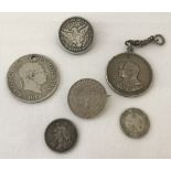 A small collection of silver and white metal coins some made into jewellery.