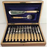 An Edwardian wooden cased cutlery set of fish and fruit knives & forks with matching servers.