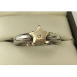 A modern design silver and 14ct gold star ring set with a small central diamond.