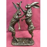 A bronze figure depicting a pair of boxing hares.