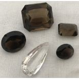 4 loose smoked quartz gemstones together with a teardrop cut rock crystal stone.