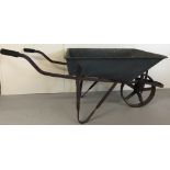 A vintage wheelbarrow. Galvanized metal body with cast iron frame, handles and wheel.