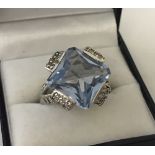 A 925 silver ladies dress ring set with large central square cut pale blue stone.