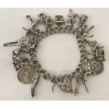 A vintage silver double link charm bracelet, with padlock and safety chain & holding 18 charms.