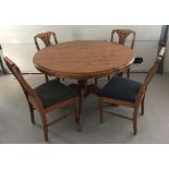 A modern honey pine pedestal based extending dining table and 4 matching chairs.