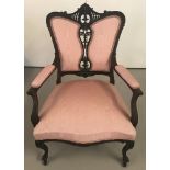 A Victorian bedroom chair with decorative carved detail to back, arms and legs.