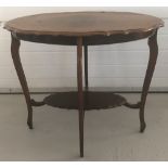 A vintage dark wood oval shaped occasional table with shaped detail to top and undershelf.