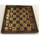 An Antique hinged travelling wooden chess board with red and white ivory chess pieces by Jaques.