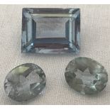 A large emerald cut blue topaz gemstone together with 2 round cut blue topaz gemstones.