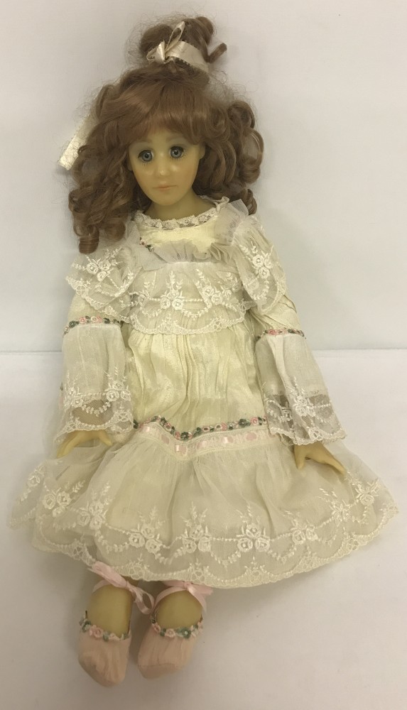 A modern blue eyed wax doll with wired soft body and legs in a traditional vintage style outfit.