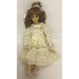 A modern blue eyed wax doll with wired soft body and legs in a traditional vintage style outfit.