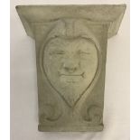 A modern heavy concrete wall hanging ornament of a jesters face.