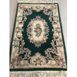 A green and cream Chinese style floral rug with tassled ends.