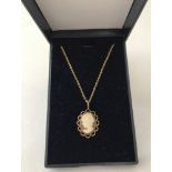 A 9ct gold cameo pendant with scalloped edge detail. On an 18" 9ct gold fine belcher chain.