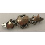 An antique silver and rose gold sweetheart brooch with ivy leaf and central heart decoration.