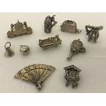 A collection of 10 vintage silver and white metal charms, some with movable parts.