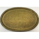 A large heavy brass oval tray with hammered Persian decoration.