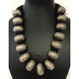 An ethnic style large white metal, ribbed bead and cotton necklace.