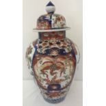 A large oriental vase in the Imari style, with decorative panels and a lid with finial top.