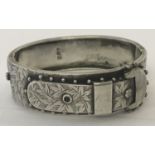 An antique silver bracelet with engraved detail and buckle design to front.