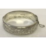 A vintage silver hinged bangle with half floral engraved decoration.