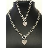 A silver belcher chain necklace and matching bracelet with T bar clasp and suspended heart charm.