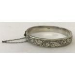 A vintage silver hinged bangle with engraved detail to one half.