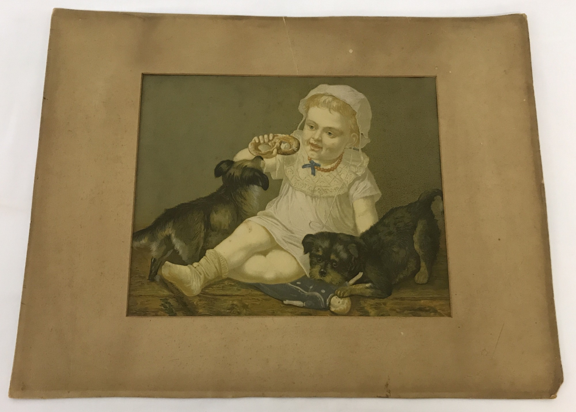 A vintage mounted but unframed oleograph of a young child with dogs.