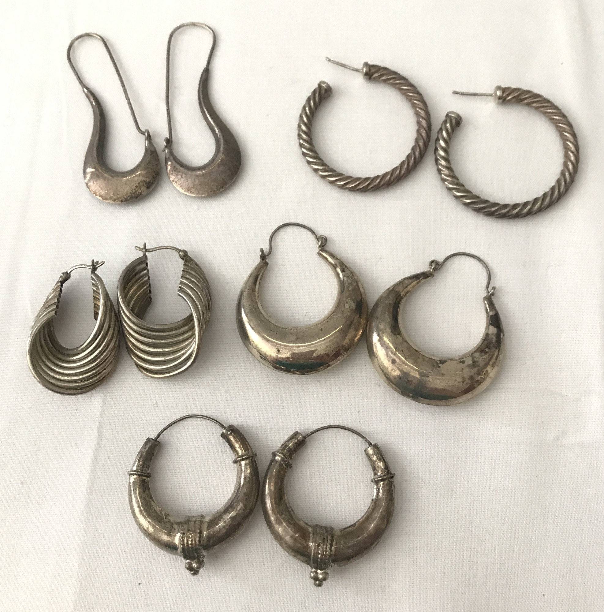 5 pairs of silver and white metal hoop and creole style earrings.