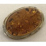An oval amber and white metal brooch.