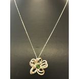 A decorative modern design flower pendant set with central green stone. Back of pendant marked 925.