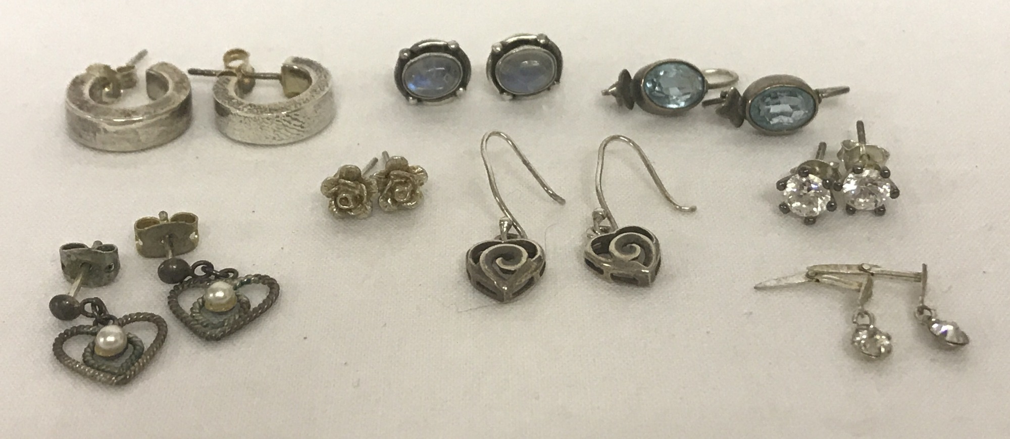 8 pairs of silver and white metal earrings to include stud style, hoops and drops.