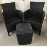 A pair of modern black plastic woven effect garden armchairs.
