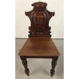 A vintage mahogany hall chair with carved scroll decoration to back and turned front legs.