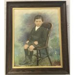 A framed and glazed oil painted photographic portrait of a young boy seated.