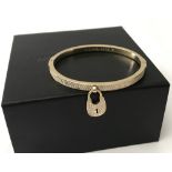 A Michael Kors gold tone hinged pave set bangle with padlock charm.