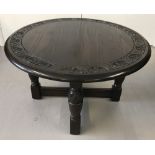 A heavy circular dark oak 'Jaycee' coffee table with decorative floral carving to perimeter.